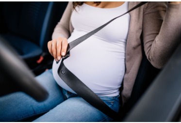Pregnant driver putting on their seatbelt