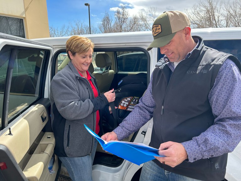 Angel Giffin, Colorado State Patrol’s Child Passenger Safety Training Coordinator, and a student from the course, stand outside a car reviewing instructions on proper car seat installation as they work on a car seat.