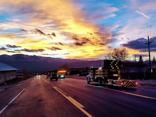 A group of CDOT trucks on a road at sunset