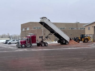 Semi dumping load of sand into parking lot. 